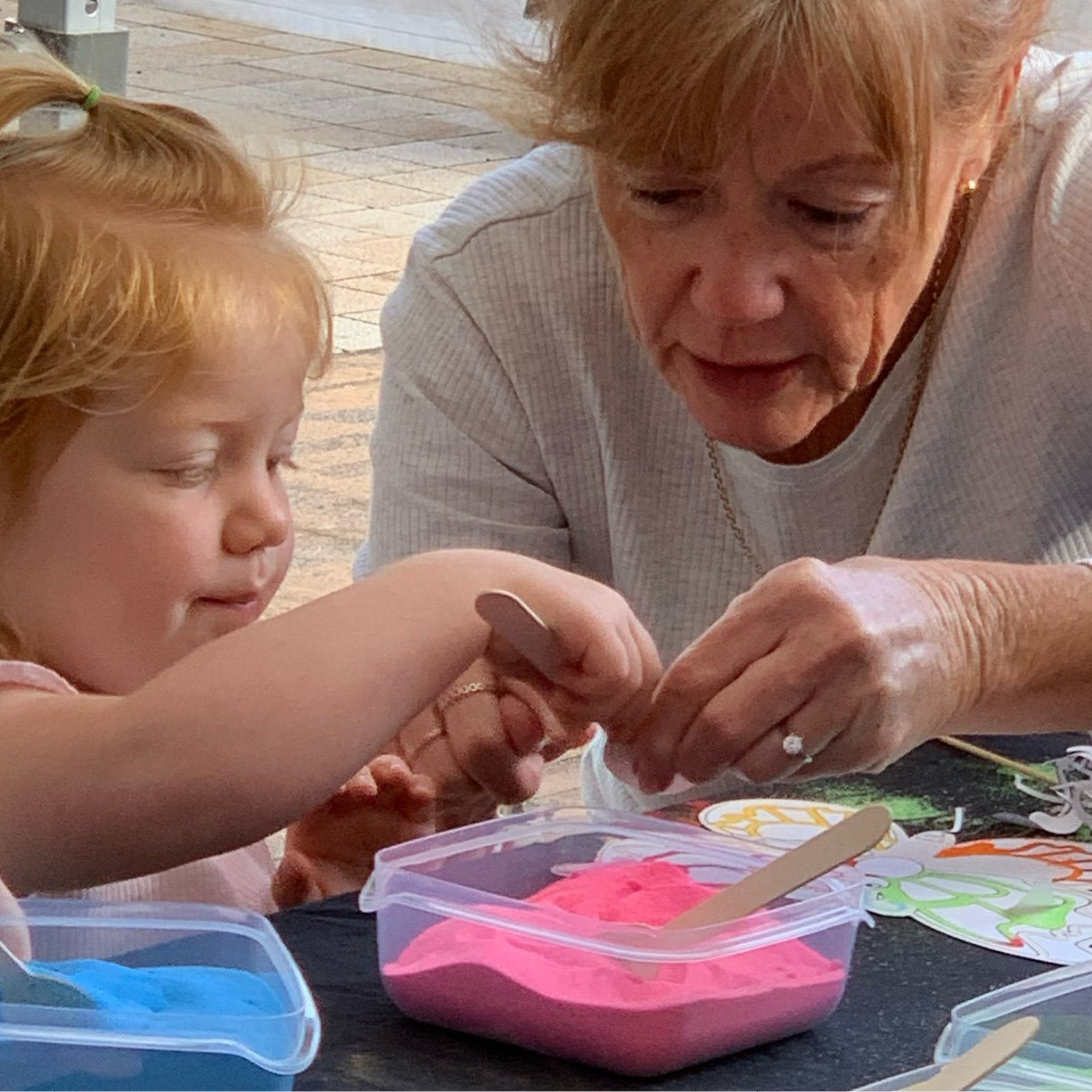 Adult and child doing sand art together.