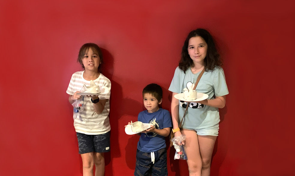 Three children holding air dry clay rabbit vessel.