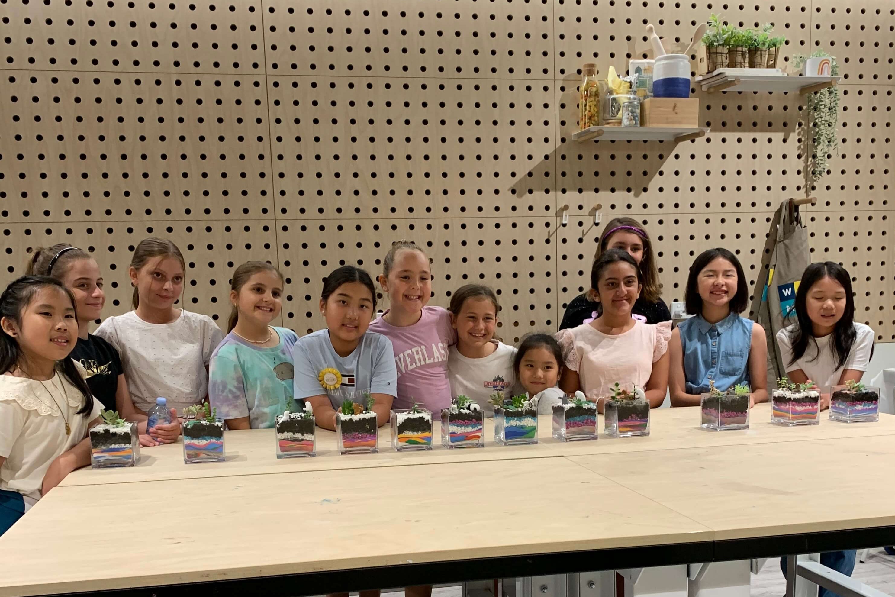 Children proudly displaying their finished terrarium creations.