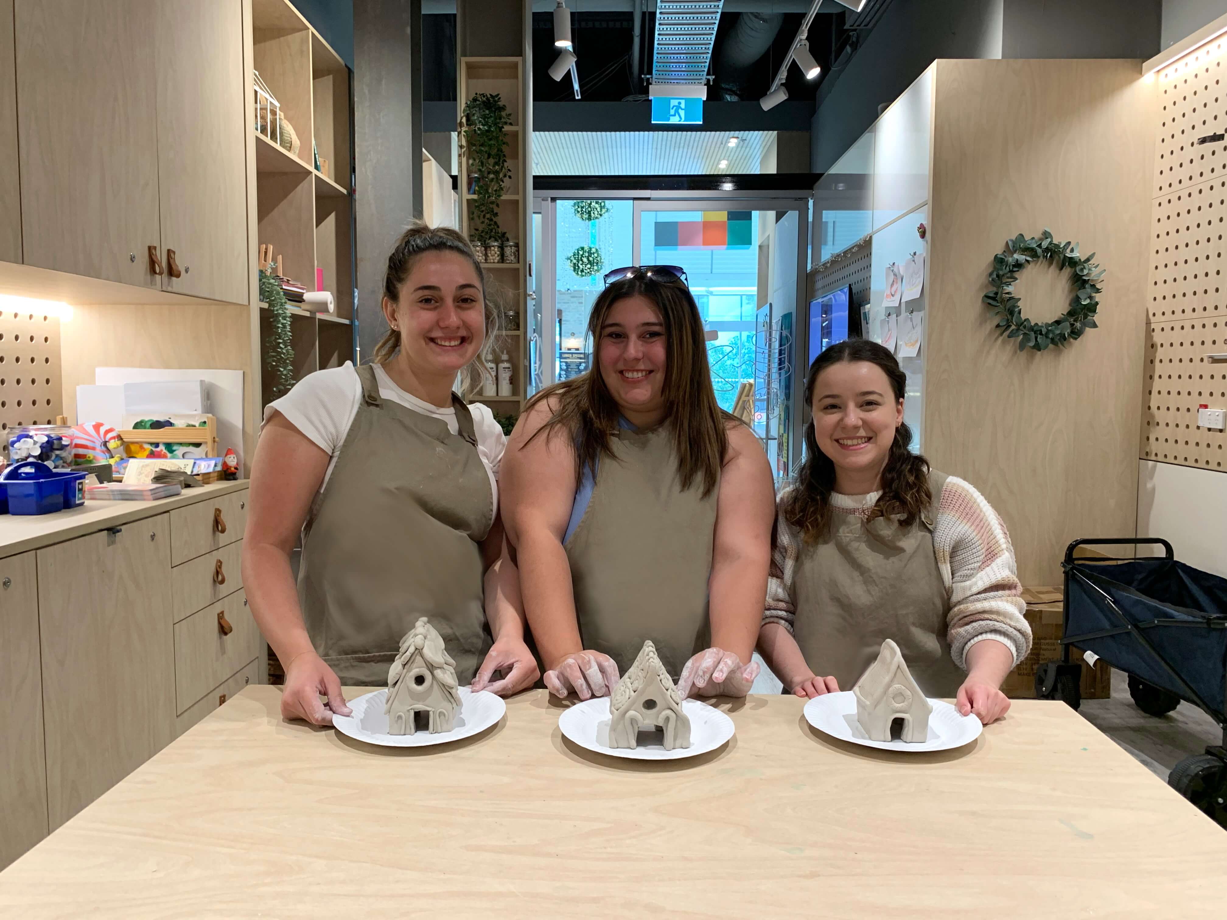 Three women with clay gingerbread house 
