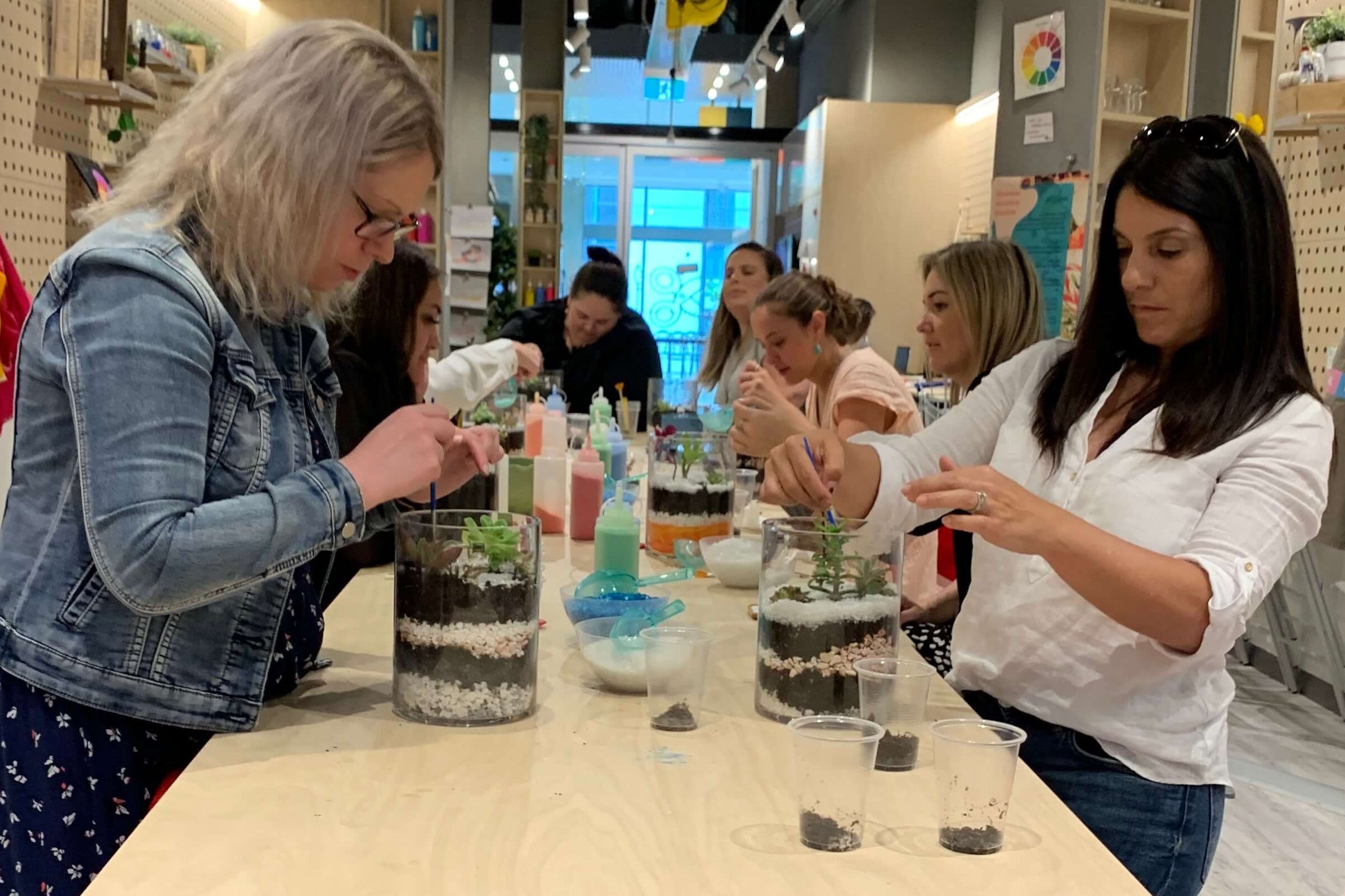 A group of women around the table building terrariums