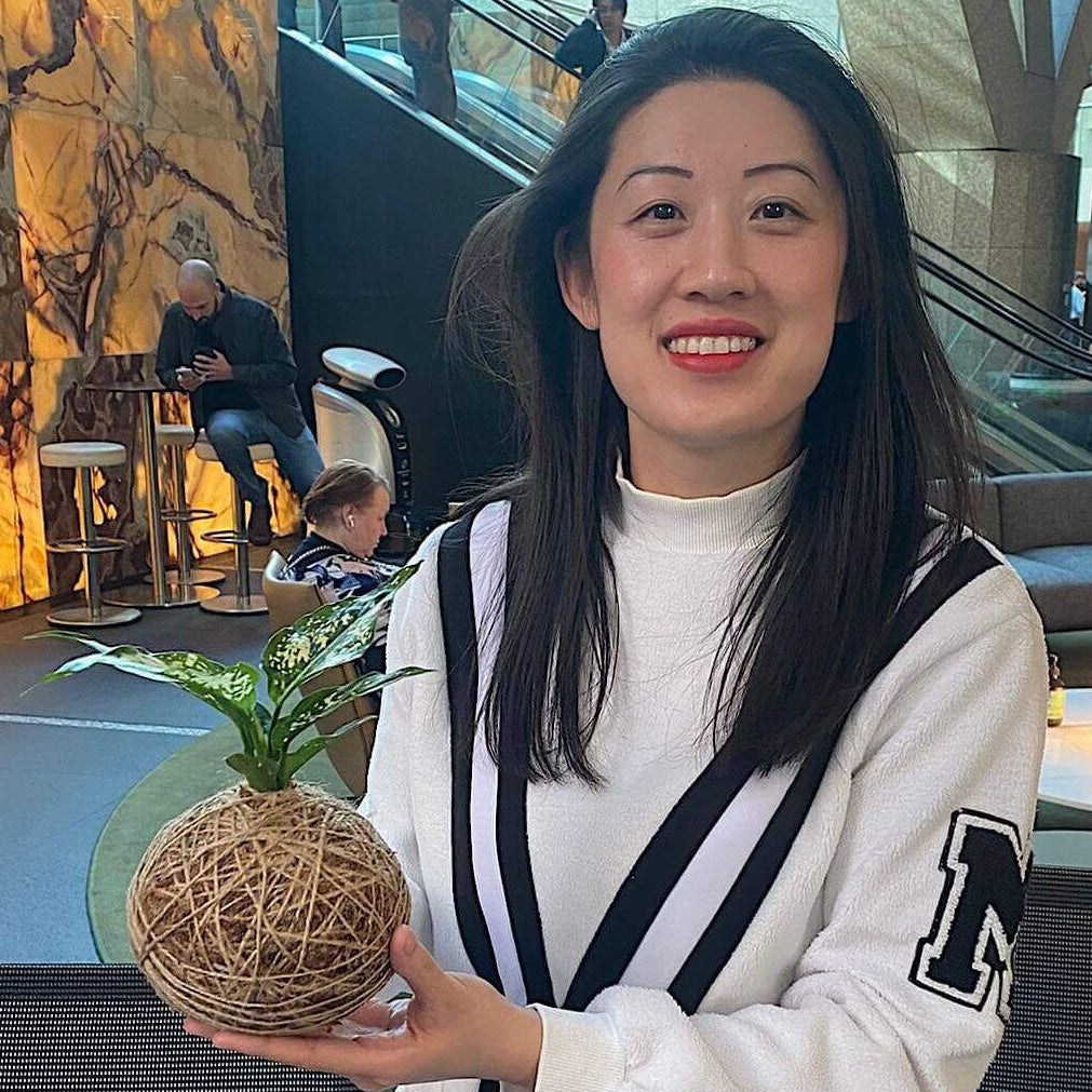 Woman holding a kokedama in a modern indoor setting