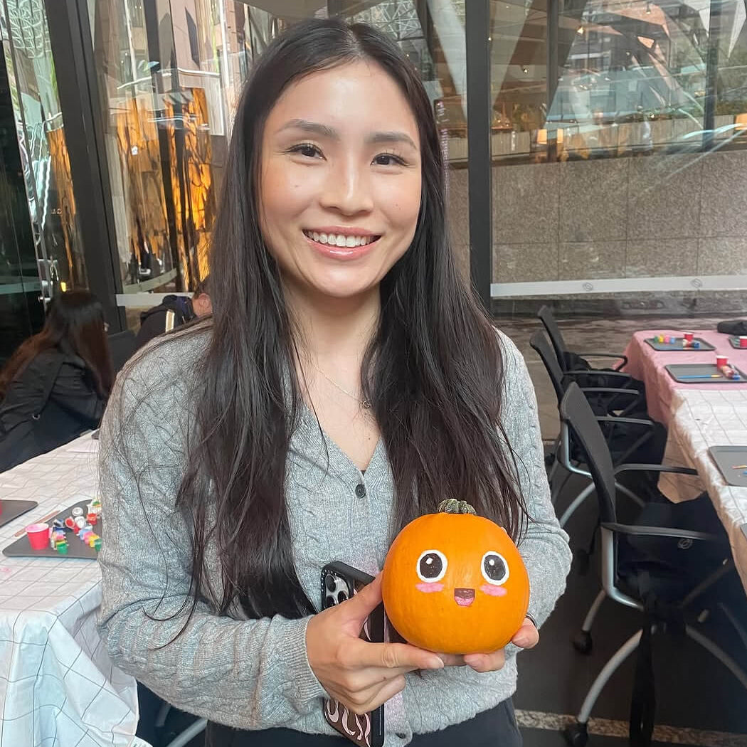 A woman is holding a painted Halloween pumpkin