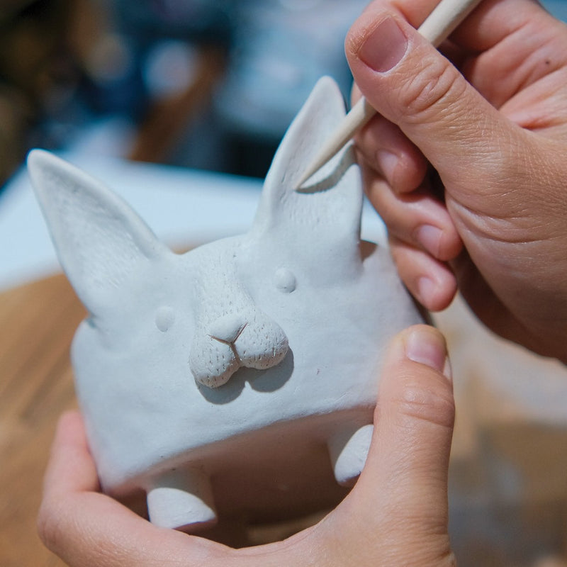 Person adding textures to rabbit container sculpture from air dry clay.