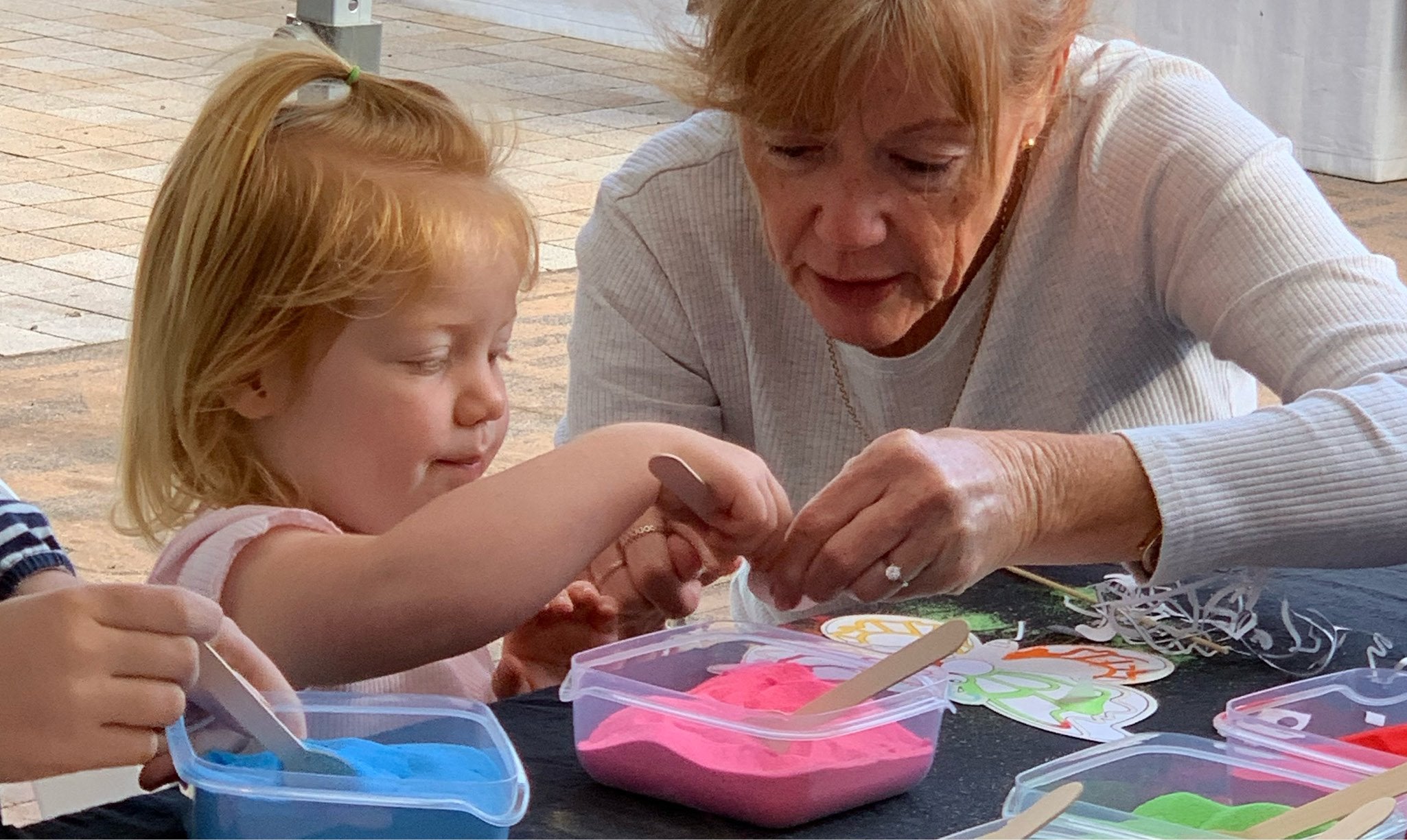 Adult and child doing sand art together.