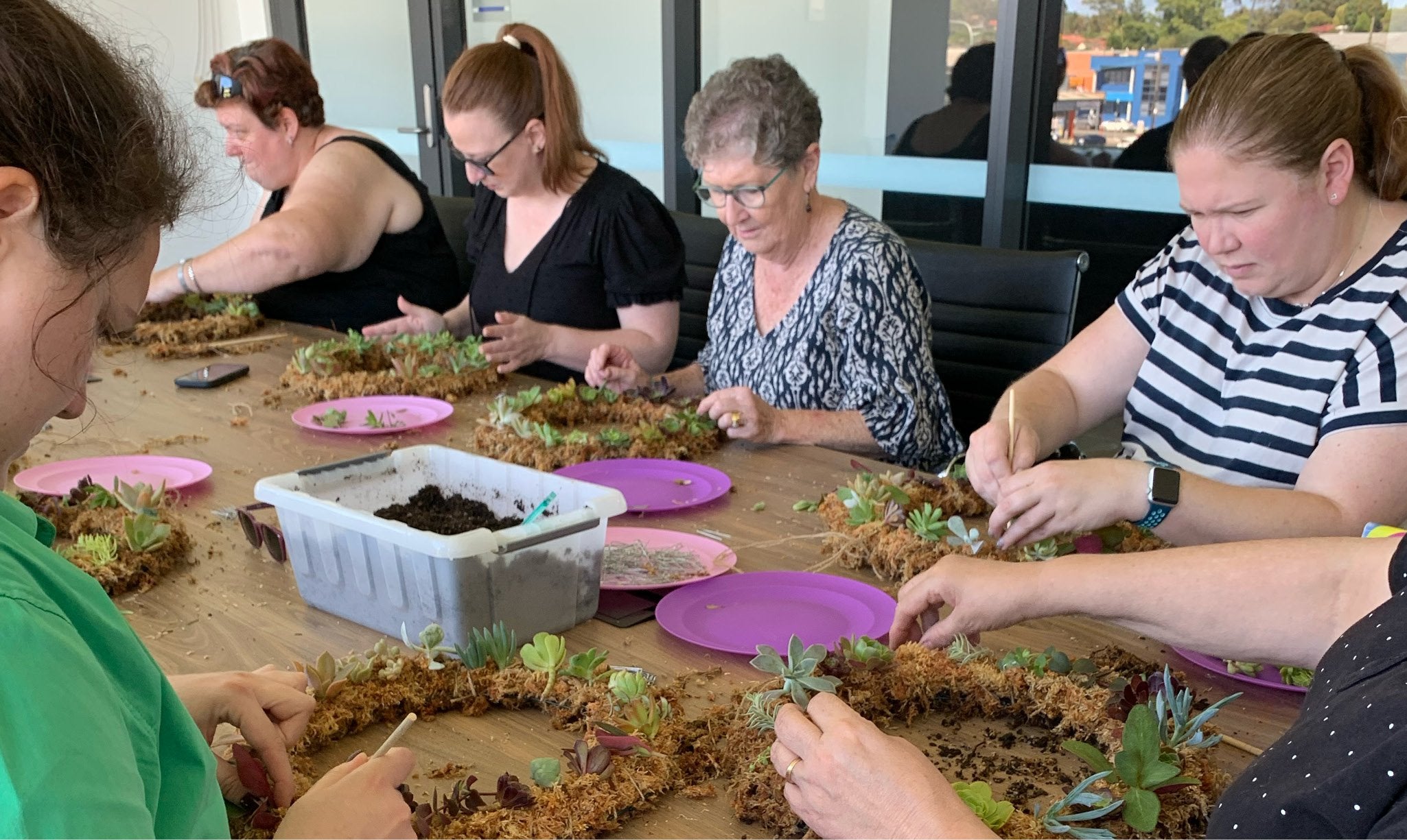 Group of people working on creating succulent wreaths during workshop.