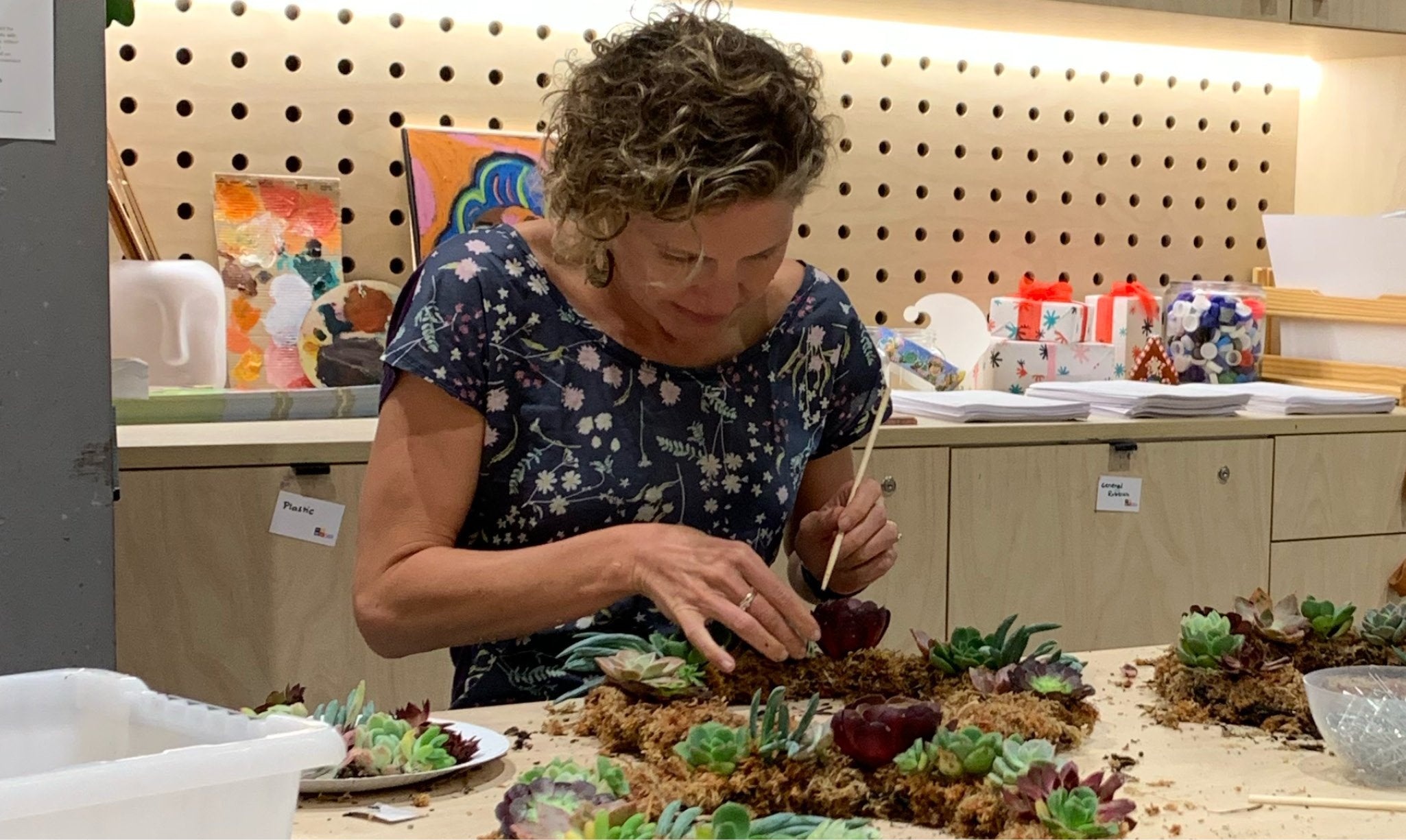 Person working on succulents wreath during workshop.