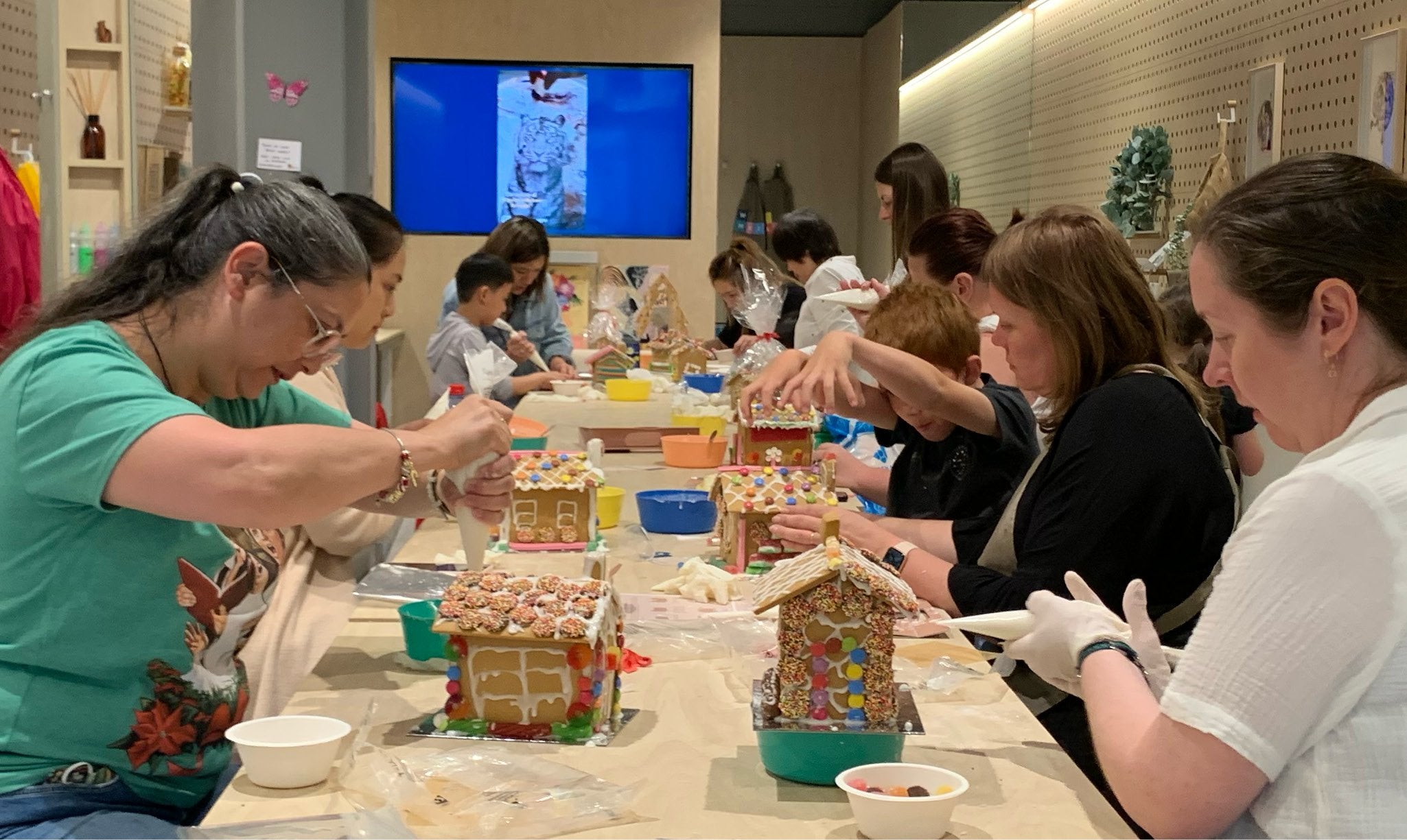Family and friends making gingerbread houses during workshop.