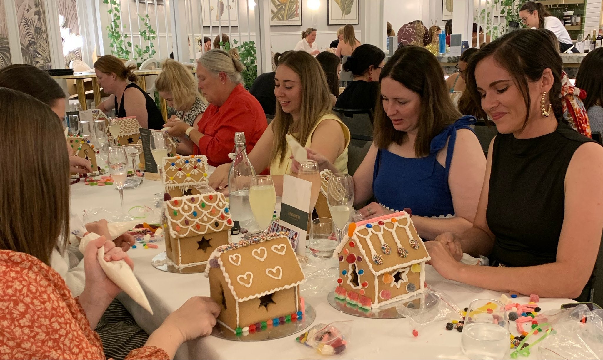 People making gingerbread houses at a festive event.
