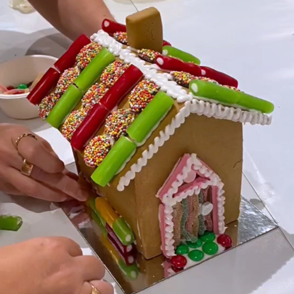 Gingerbread house being decorated with icing and lollies during workshop.
