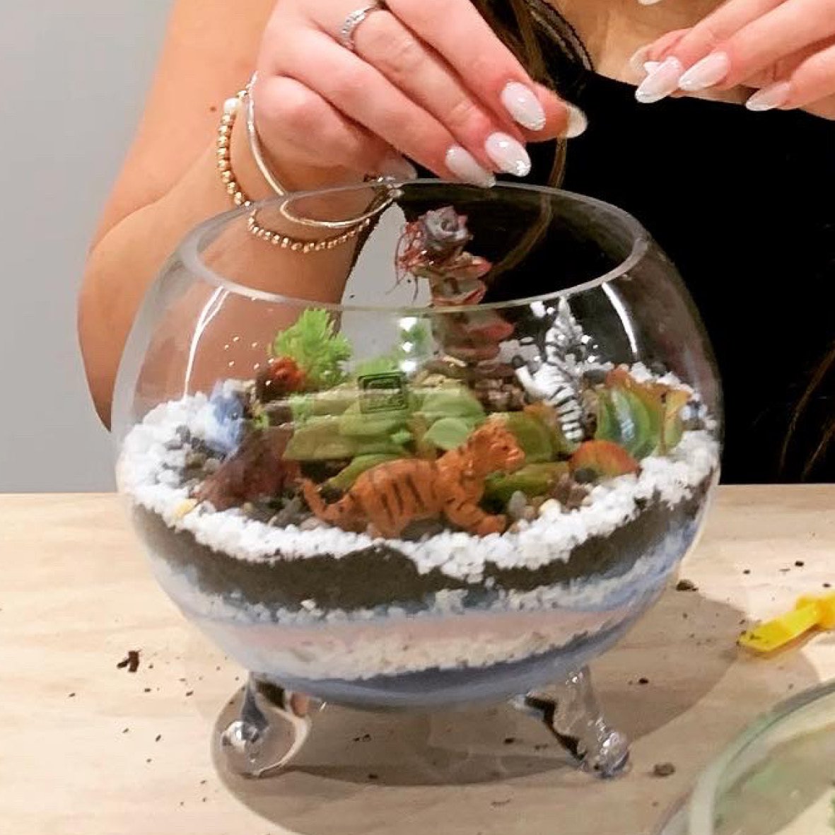 A woman making succulents and sand terrarium during workshop.